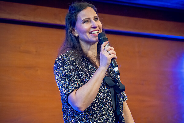 Frau spricht am Mikrofon bei einer Veranstaltung. Lächelnde Frau mit Mikrofon.