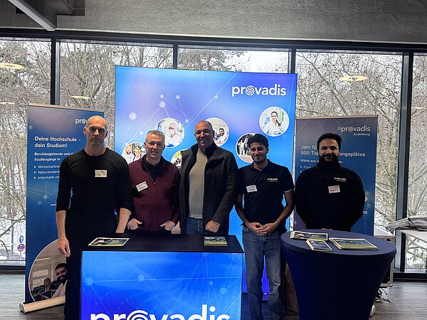 Personen am Stand von Provadis während einer Veranstaltung Fünf Personen vor einem Stand