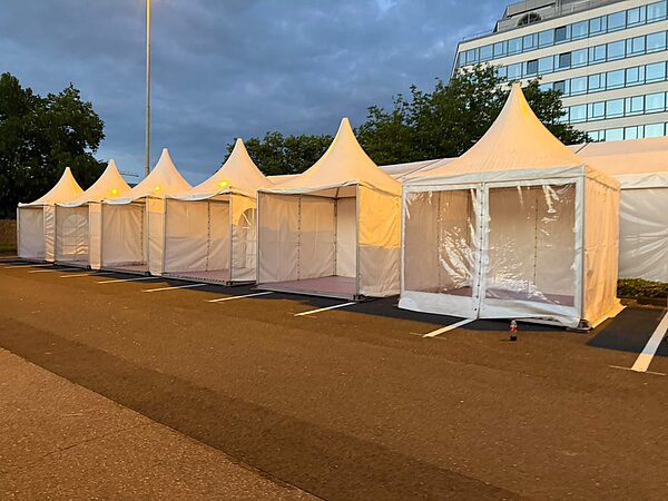 Reihe von weißen Zelten auf einem Parkplatz Weiße Zelte auf Parkplatz
