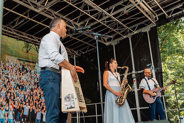 Drei Musiker live auf der Bühne während eines Events Musiker auf der Bühne bei einem Auftritt