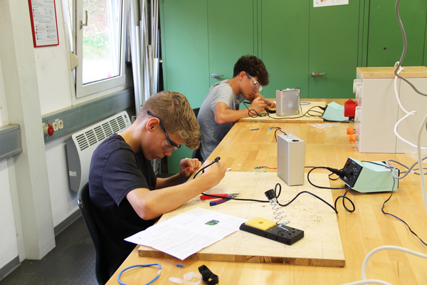 Zwei Schüler arbeiten an Elektronikprojekten.