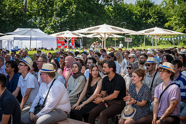 Große Menschenmenge bei einer Veranstaltung im Freien Publikum im Freien, viele mit Hüten
