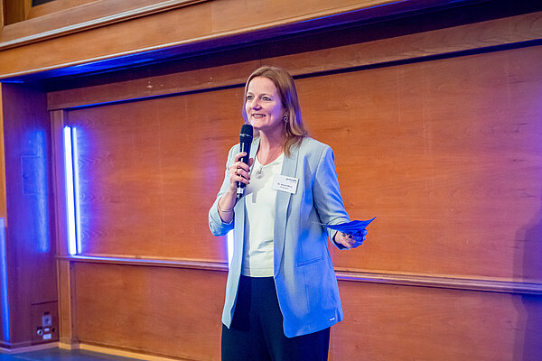 Frau präsentiert bei einer Veranstaltung mit Mikrofon. Frau spricht mit Mikrofon.