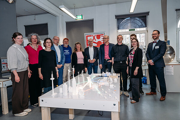 Menschen stehen vor einem Stadtmodell in einem Raum. Gruppe von Personen vor Modellen.