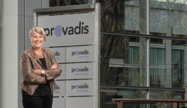 Frau lächelt vor der Provadis-Hauptzentrale Frau vor der Provadis-Firmenfassade
