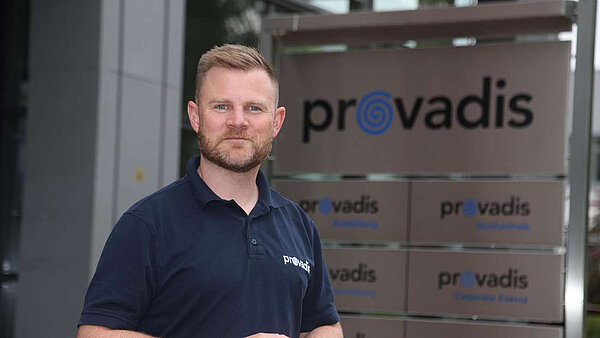 Mann steht vor dem Provadis Unternehmenslogo. Zwei Ehrenämter und ein Job – wie Raphael Borst das hinbekommt