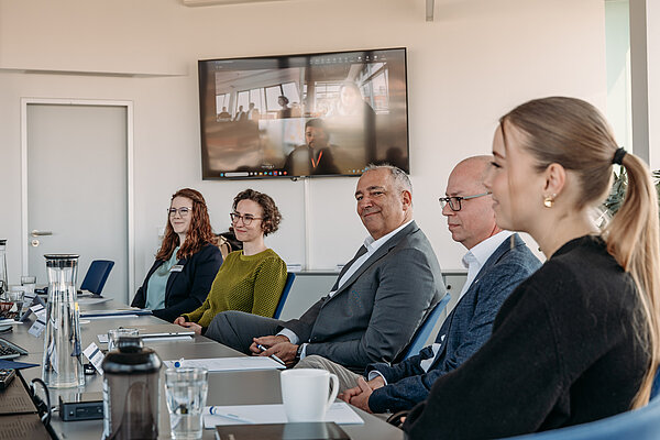 Diskussion in einem Konferenzraum mit Videokonferenz Besprechung mit fünf Teilnehmern