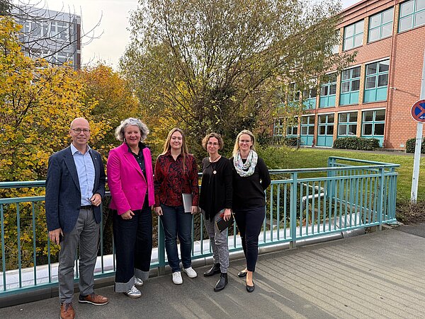 Fünf Personen stehen auf einer Brücke des Provadis Campus vor herbstlich gefärbten Bäumen und einem Backsteingebäude. Anlass ist ein Austausch zwischen Provadis und dem Fachverband PlasticsEurope Deutschland