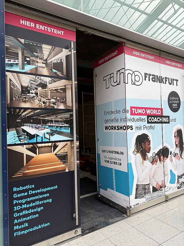 Große Werbetafeln am Eingang des künftigen TUMO Frankfurt zeigen Visualisierungen der zukünftigen Lernräume sowie Informationen zu kostenlosen Workshops für Jugendliche von 12 bis 18 Jahren in Bereichen wie Robotik, Game Development und Animation.