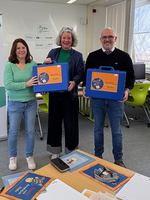 Drei Personen mit Kisten in einem Raum