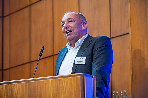 Mann hält eine Rede vor einem Publikum. Mann spricht am Podium.